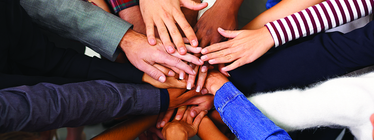 Shot of a diverse group of business people joining their hands in a symbol of unity